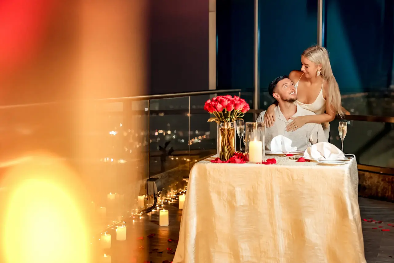 Romantic indoor rooftop proposal dinner with candles and roses overlooking Dubai city lights