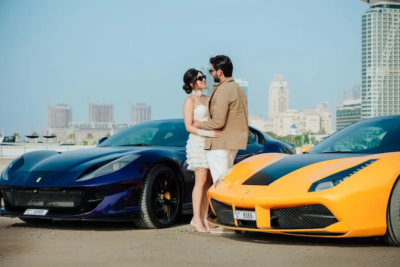 Pre-wedding photoshoot couple posing with luxury supercars in Dubai with city skyline